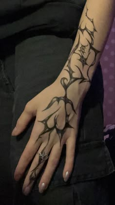 a woman's hand with black ink on her left arm and the wrist is decorated with vines