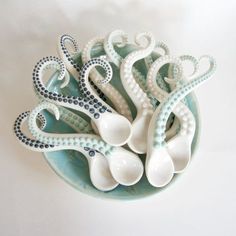 an octopus sculpture is sitting in a bowl on the table next to some spoons