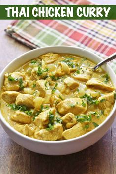 a white bowl filled with chicken curry on top of a wooden table