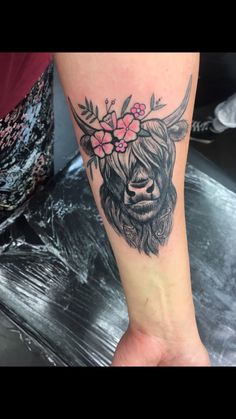 a woman's foot with a tattoo of a cow and flowers on it,