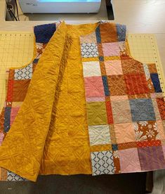 a quilt is laying on top of a table next to a sewing machine and cutting mat