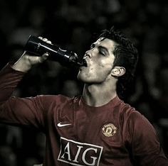 a man drinking from a bottle while standing in front of a crowd