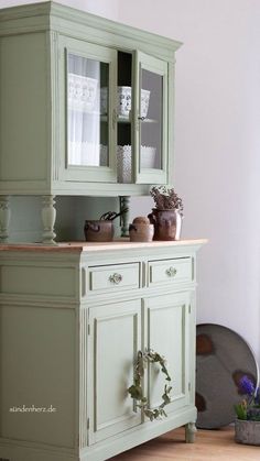 a green china cabinet with glass doors and drawers