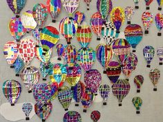 many colorful hot air balloons are hanging on the wall in an art project that is being displayed