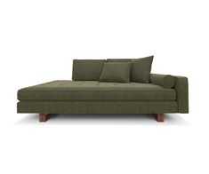 a green couch sitting on top of a white floor next to two brown pillows and wooden legs