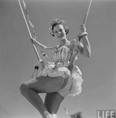 an old photo of a woman on a swing