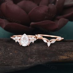 an image of two wedding rings on top of a tree branch with flowers in the background