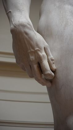 a close up of a person's hand on the back of a white statue