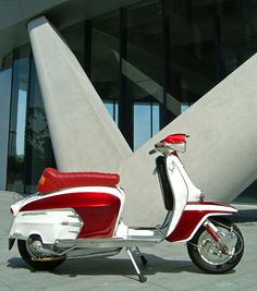 a red and white scooter parked in front of a building