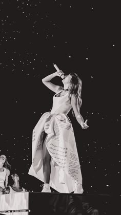 a woman in a dress standing on top of a stage with her hands behind her head