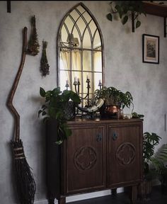 a room with a mirror, potted plants and a wooden cabinet