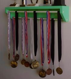 several medals are hanging on a green shelf