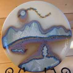 a white and blue plate sitting on top of a metal stand next to a wooden wall