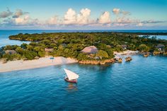 an aerial view of a small island with a sailboat in the water