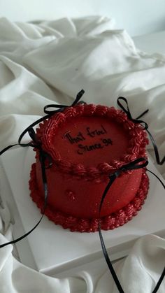 a red cake with writing on it sitting on top of a white tablecloth covered bed