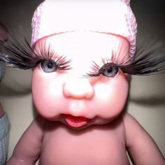 a close up of a baby with fake eyelashes on it's head