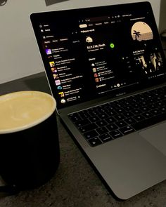 an open laptop computer sitting on top of a table next to a cup of coffee