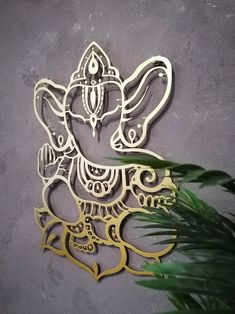 an intricately carved metal ganeshi on a wall next to a potted plant