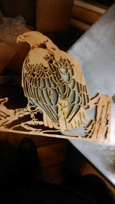 a wooden cut out of an eagle sitting on top of a piece of wood