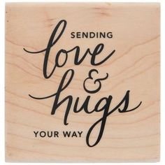 a wooden stamp with the words sending love and hugs your way on it's side