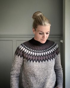 a woman standing in front of a door wearing a gray and black sweater with an argyle pattern