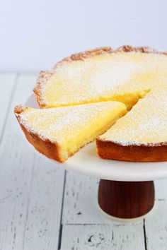 a cake that has been cut into slices on a white plate and is sitting on a wooden stand