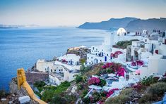 a view of the ocean and buildings on top of a hill in oia, greece