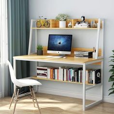 a desk with a computer on top of it next to a chair and potted plant