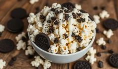 a bowl filled with oreo cookies and white chocolate popcorn on top of a wooden table