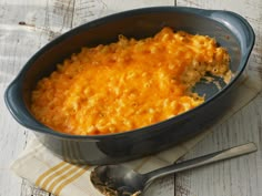 a casserole dish with meat and cheese in it on a napkin next to a spoon