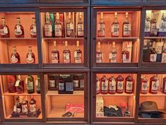 several bottles of alcohol are on display in a case with wooden shelves and glass doors