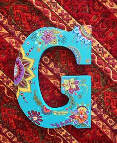 the letter c is painted with colorful flowers and paisley designs on it's sides