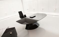 a modern glass table with black chairs in an empty room on white flooring and walls