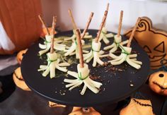 there are many small white flowers on the black cake plate with sticks sticking out of it