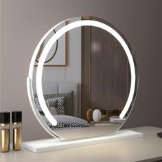 a round mirror sitting on top of a white table next to a dresser and lamp