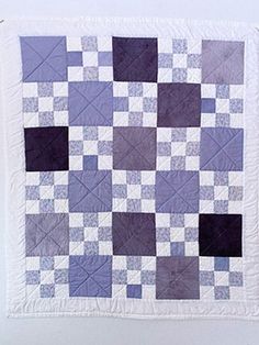 a purple and white quilt hanging on a wall