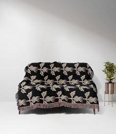 a black couch sitting next to a potted plant on top of a white floor