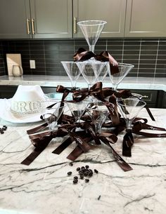 some wine glasses are sitting on a marble counter top with brown ribbon around the edges