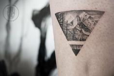 a man with a tattoo on his arm has a mountain and forest scene in the shape of a triangle