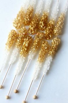 several gold and white candy sticks with sprinkles on them are arranged together