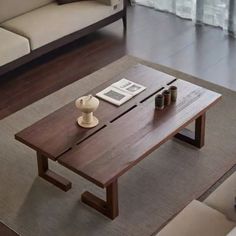 a coffee table sitting on top of a rug in front of a couch next to a window