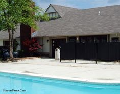 a pool in front of a house with a fence around it and a water heater