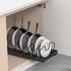 the dish rack is holding many plates and pans in it's cabinet drawer