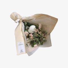 a bouquet of flowers is wrapped in a white paper and tied to a ribbon with a tag