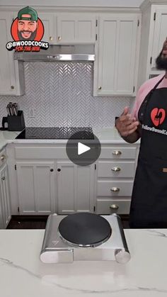 a man standing in a kitchen next to a stove top oven and holding a frying pan