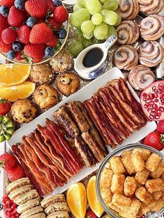 an assortment of food is displayed on a platter with fruit and pastries around it