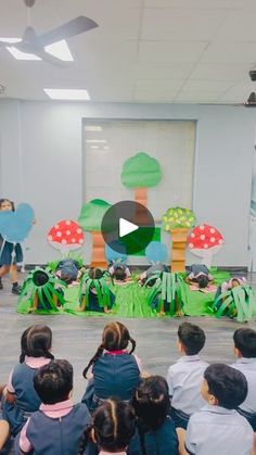 a group of children sitting in front of a stage with paper cutouts on it