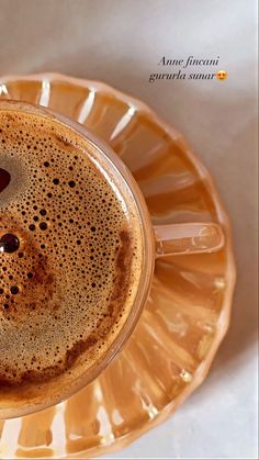 a cappuccino in a yellow glass cup on a saucer with a spoon