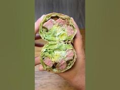 a hand holding two pieces of artichoke with meat and lettuce in it