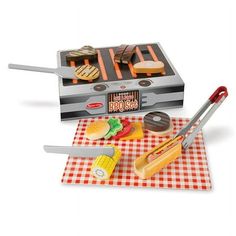 a toy barbecue grill with tongs and other items on a checkered table cloth